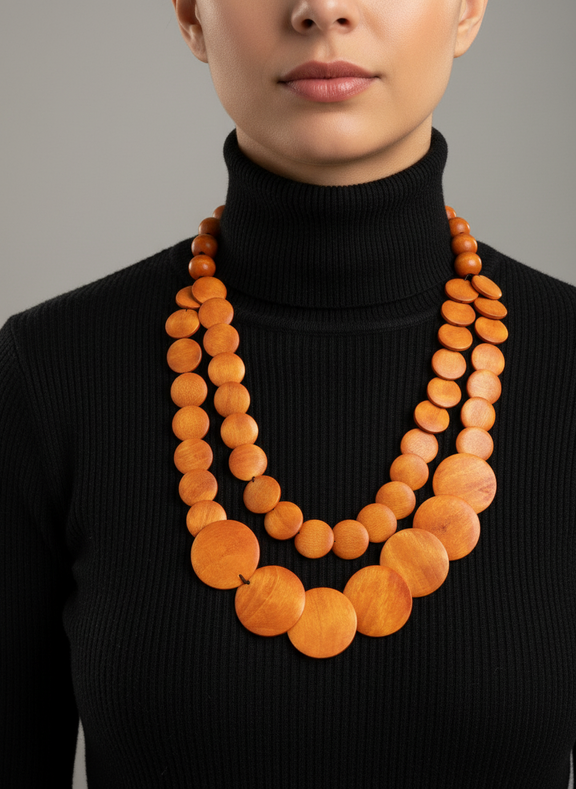 Person wearing a black turtleneck with a long, orange beaded necklace.