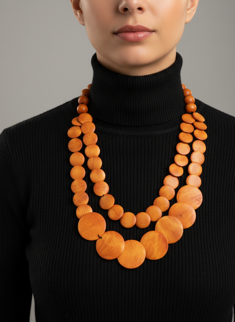 Person wearing a black turtleneck with a long, orange beaded necklace.