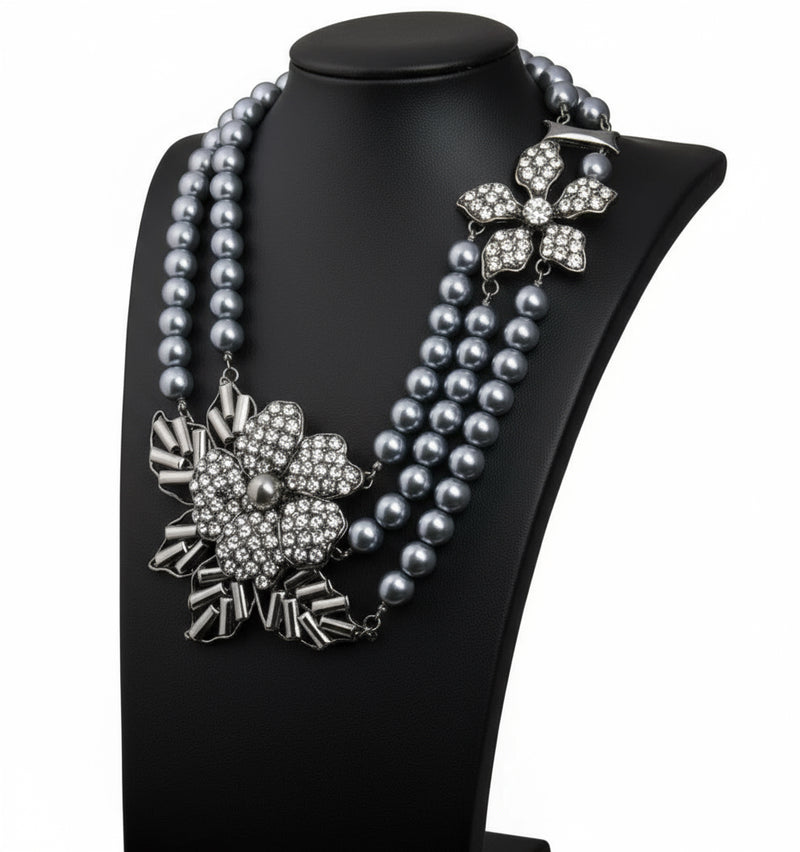 Gray pearl necklace with floral silver pendants on a black stand