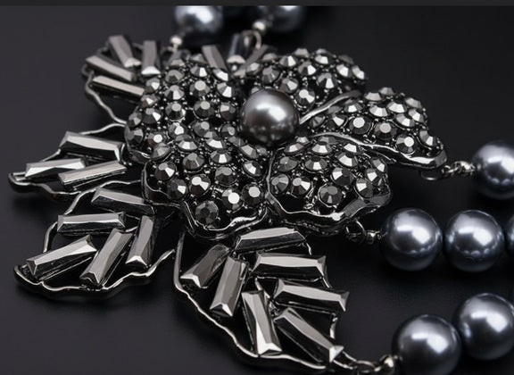 Silver brooch with gemstones and pearls on a dark background