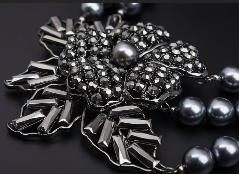 Silver brooch with gemstones and pearls on a dark background