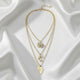 Gold necklaces with various pendants on a white fabric background
