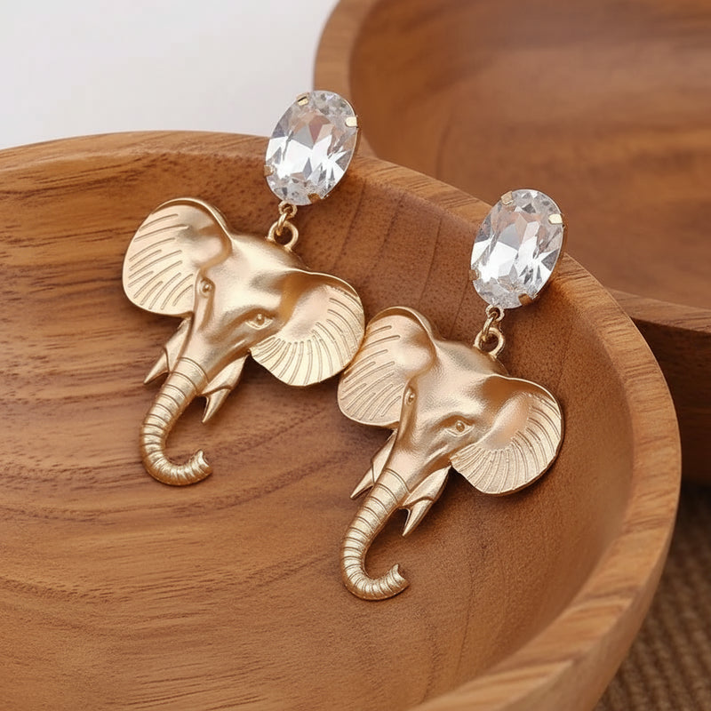 Gold elephant earrings on a light gray background